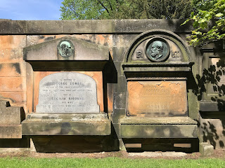 A photo of two gravestones with effigies on them of the faces of the occupants lying beneath in their graves.  Photograph by Kevin Nosferatu for the Skulferatu Project.