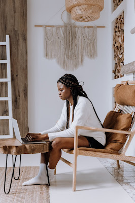 white room with retro furniture and black woman on laptop