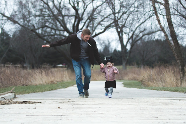 A father running with his daughter while holding her hand