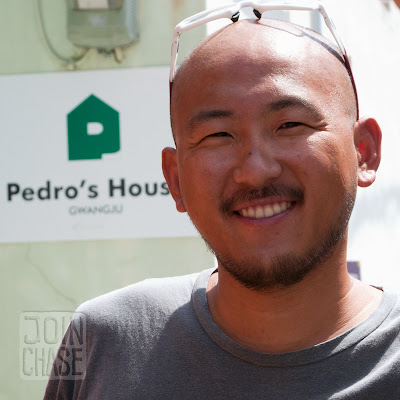 Pedro, a Korean man in front of a sign for Pedro's House in Gwangju, South Korea.