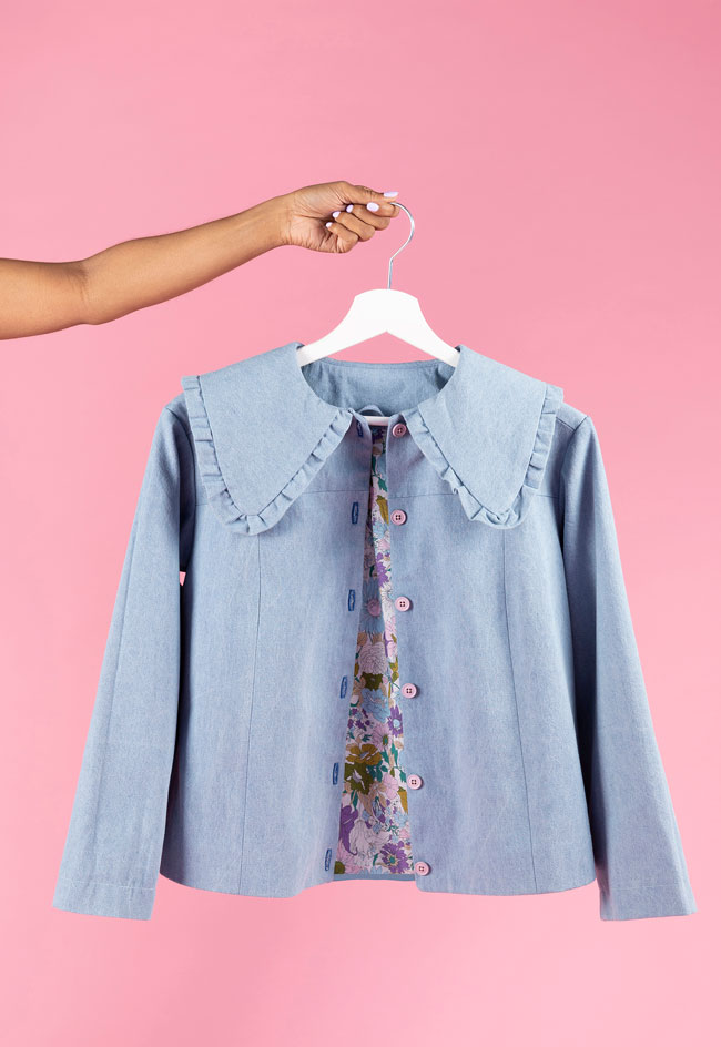 Hand holding denim jacket with oversized prairie collar on a hanger, made using the Sonny jacket pattern