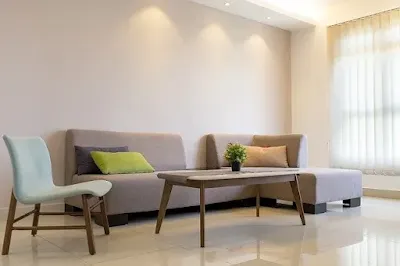 Imagem ilustrativa de uma sala de apartamento com sofá bege, cadeira branca ilustrando texto sobre sublocação