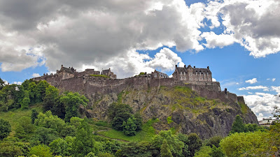 Large grey castle on a rocky outcrop above Edinburgh's Princes Street Gardens