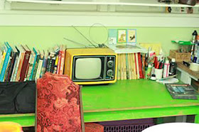 Beth Spencer's work space, with a green desk, books, and a small TV.