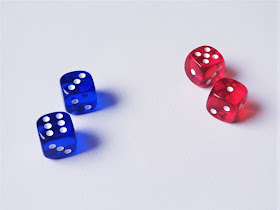 na zdjęciu znajdują się cztery kostki, dwie w kolorze niebieskim z wynikami sześć i trzy oraz dwie w kolorze czerwonym z wynikami pięć i jeden
