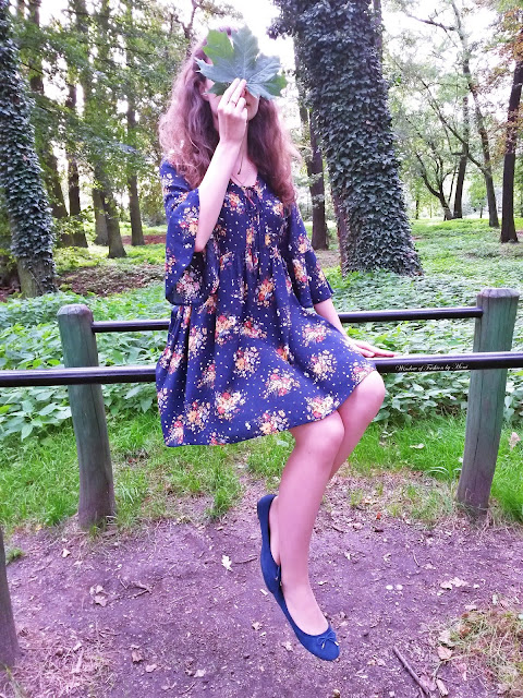 Dziewczyna w sukience z twarzą zakrytą liściem