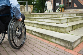 Man in a wheelchair facing a short set of stairs