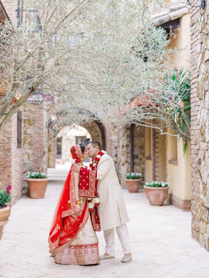 bride and groom in red and tan kissing