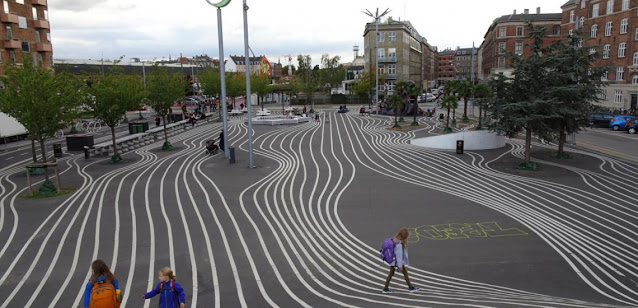 Un dessin de lignes parallèles blanches met en valeur le sol sculpté de l'espace public Superkilen, à Copenhague