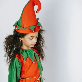 A very sad girl child wearing a colorful joker dress.