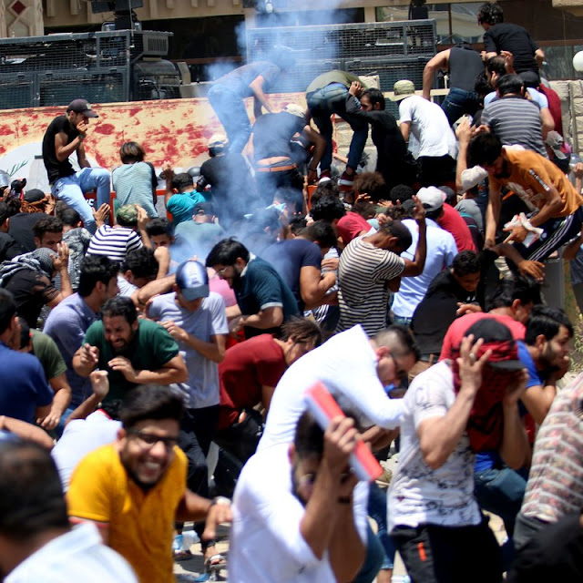 Protesters duck as Iraqi security forces fire tear gas during a demonstration against unemployment and a lack of basic 