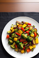 Assorted roasted vegetables on a plate, featuring bell peppers, zucchini, and broccoli.