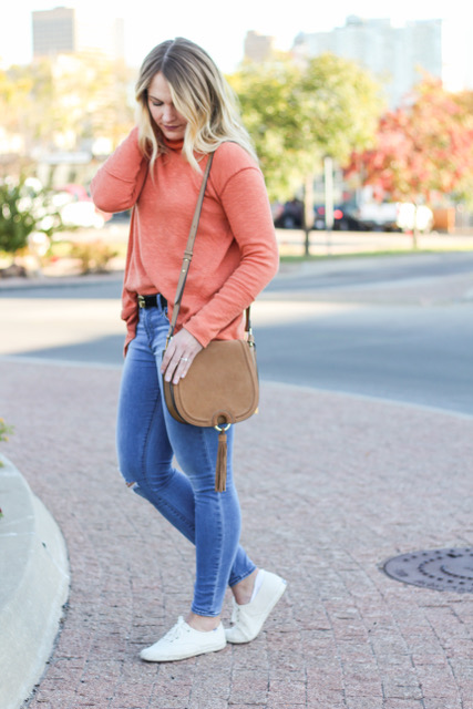 girl wearing fall colored sweater in front of autumn leaves 