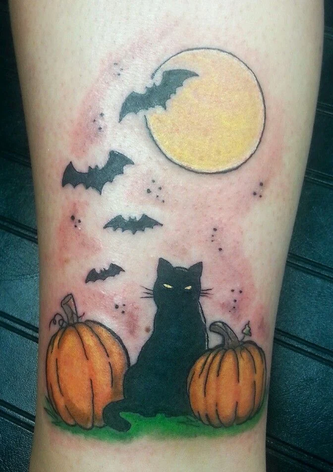 tatuaje de halloween con un gato entre dos calabazas