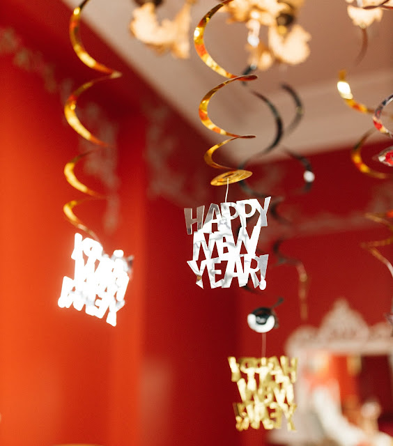 A blurred out room with "Happy New Year" decorations in focus, hanging down from the ceiling.