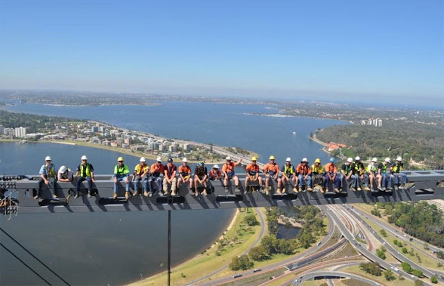 Construction workers on the skyscraper with the city in the background