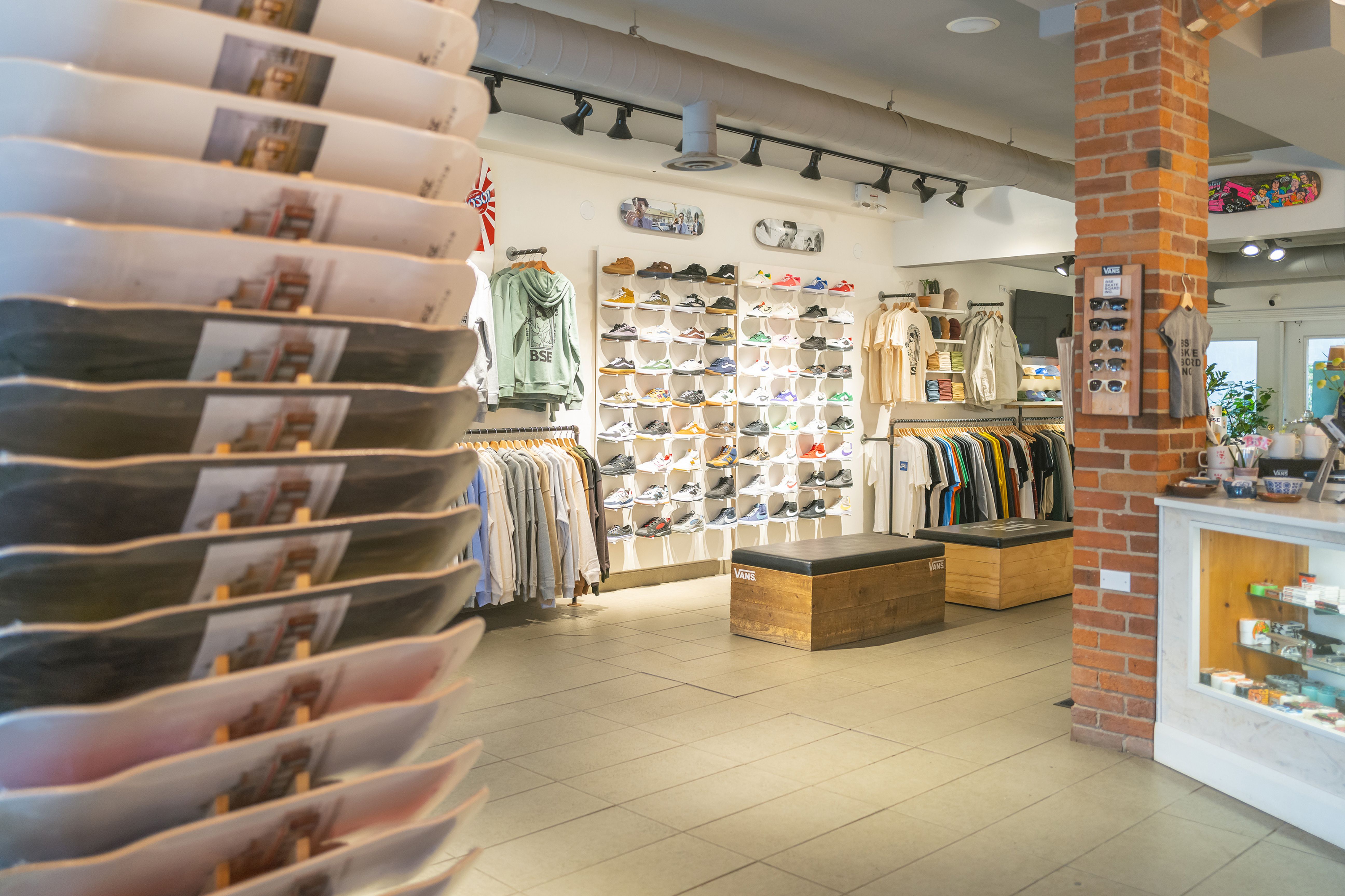 Interior of BSE Skateboard Shop with rack of skateboards and wall of shoes plus merchandise.