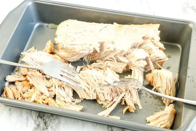 shredding pulled pork in a pan