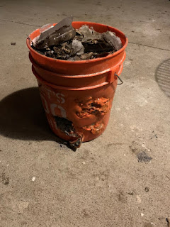 Thick orange 5 gallon bucket full of ash with lots of melt marks