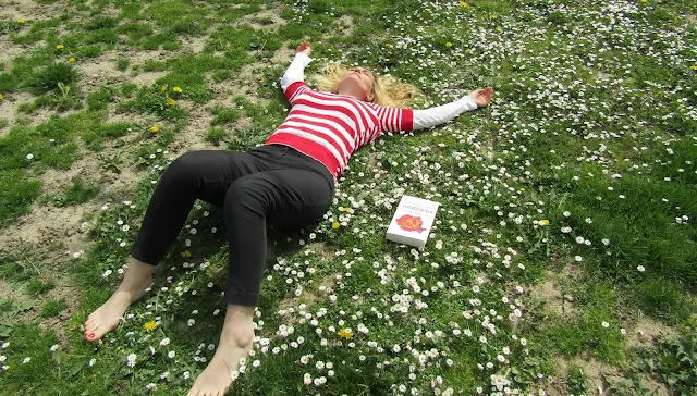 blonde woman in black trousers lying on the grass