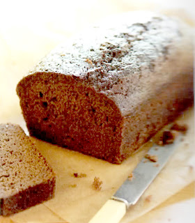 Classic gingerbread, baked in a loaf tin, turned out onto a wooden board and sliced