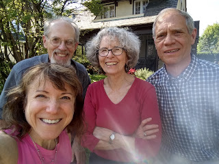 A selfie of me, David, Cécile, and Mark in a suburban yard with trees behind us.