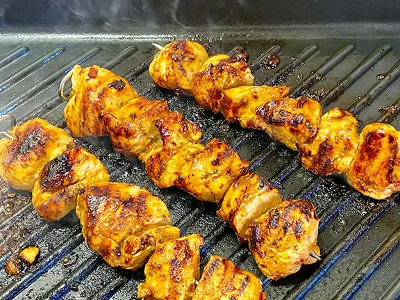 Chicken shish cooking on a griddle.