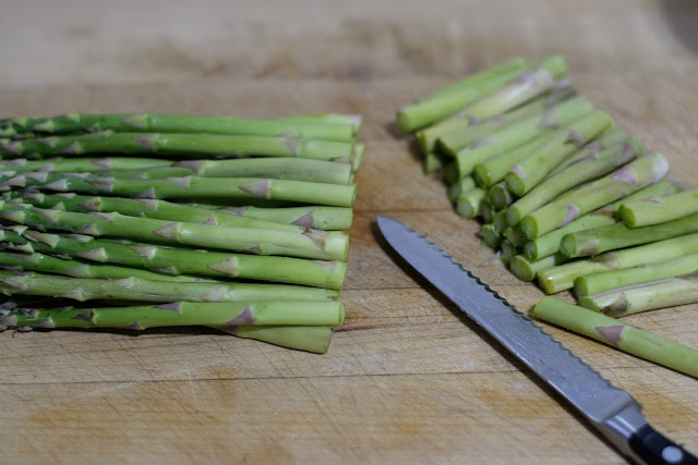 The asparagus on a cutting board with the woody ends trimmed off.