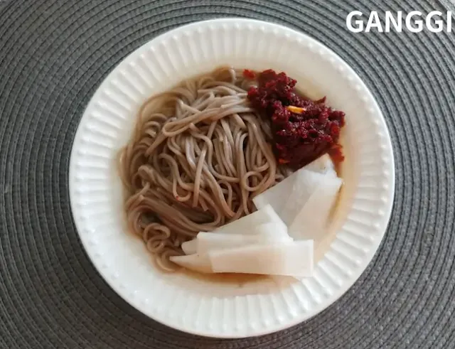 흰-접시에-절임무와-다대기가-올려진-냉면-사진