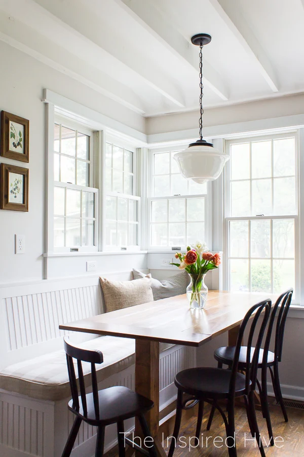 Breakfast nook with banquette bench seating, farmhouse table, and schoolhouse light