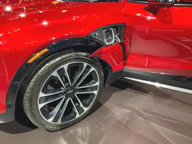 A close-up photo of the front wheel and charging port of a red Chevrolet Blazer EV.