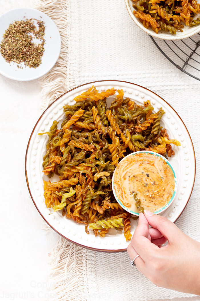 Air fryer lentil pasta chips served in a plate with tahini dip