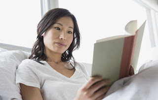 Hero Images/Getty Images - Asian woman reading in bed