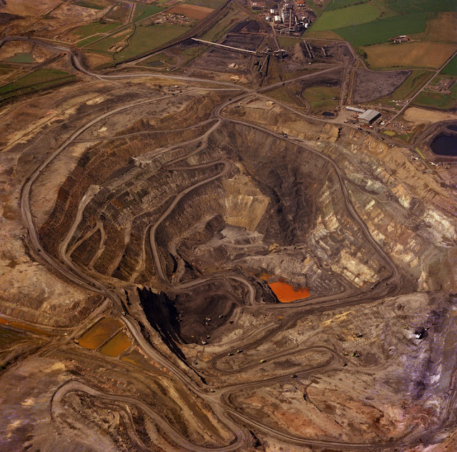 Oblique aerial view of the Westfield Opencast Coal Mine from the north-east Fife Region. Cut to extract the abnormally thick development of coals (Boglochty Beds) in the Passage Group of the Namurian of the Scottish Carboniferous succession. The excavation is about 200 metres deep and has cut through strata from just above the top of the Middle Coal Measures (Westphalian B) down to the Calmy Limestone of Namurian (E2) age. At the top are the processing plants. The Westfield Open Pit was worked by Costain Mining Limited on behalf of the National Coal Board Opencast Executive.