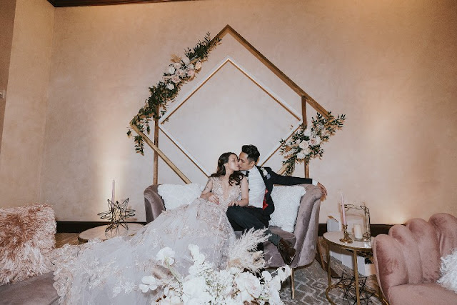 bride and groom lounding on furniture with gold diamond backdrop