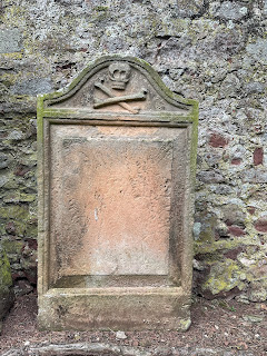 Another photo of a gravestone at Spott.  This one sits against the wall of the church.  At the top is carved the emblem of a skull and crossbones.  There is a large square space in the gravestone where the epitaph would have once been...it is now blank.  Photo by Kevin Nosferatu for the Skulferatu Project.