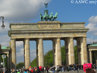 The east side of Brandenburg Gate, including a small statue on top of a chariot and horses. A large group of tourists line the bottom of the photo.