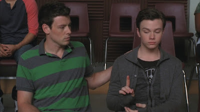 Finn trying to put his hand on Kurt's shoulder reassuringly while Kurt looks unimpressed