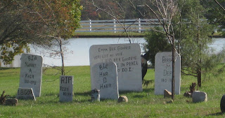 Fake tombstones with inscriptions like R.I.P Narry A. Kair, and I.B. Gott, and R.I.P. Har D. Harr, and Emma B. Goner