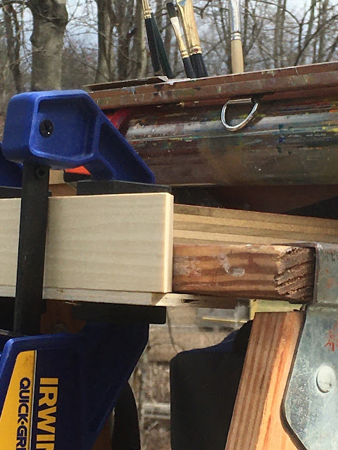 Closeup of extension hooked to stepladder top and reinforced with clamps.