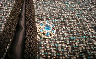 Close-up of the aquamarine blue and silver button on the black, white, and aquamarine blue tweed jacket.