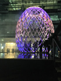 Pic of the huge, skeletal,  egg-shaped installation lit in purple