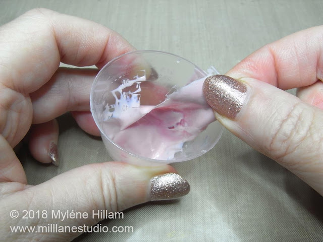 Pulling the leftover cured resin away from the walls of the plastic measuring cup.