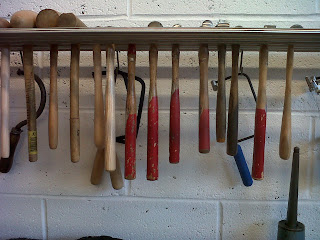 A row of tools hanging from a woodent shelf