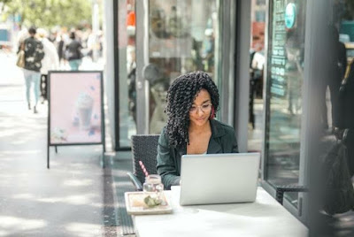 Young woman using a laptop while having a tasty beverage in a modern street cafe