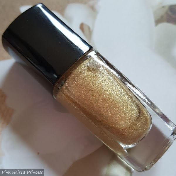 gold sparkly Lancôme nail polish bottle on floral backdrop