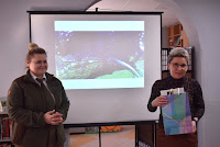 Zdjęcie przedstawia pracownika biblioteki panią Anetę Kasprzykowską wręczającą prezent pani Karolinie Piaseckiej w podziękowaniu za spotkanie.