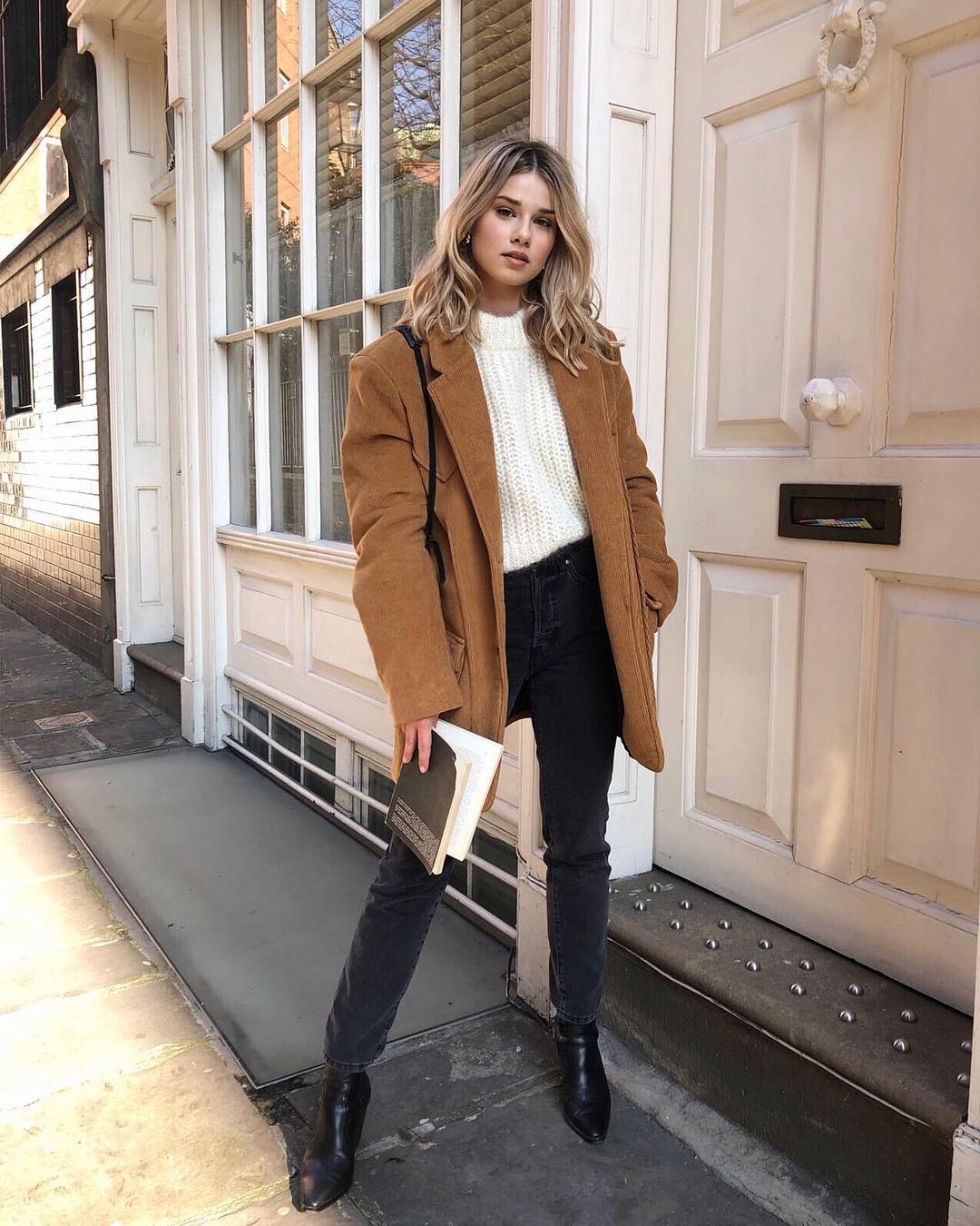 A Stylish Everyday Winter Outfit Idea to Try Now — Iga Wysocka in a camel jacket, white sweater, black jeans, and boots