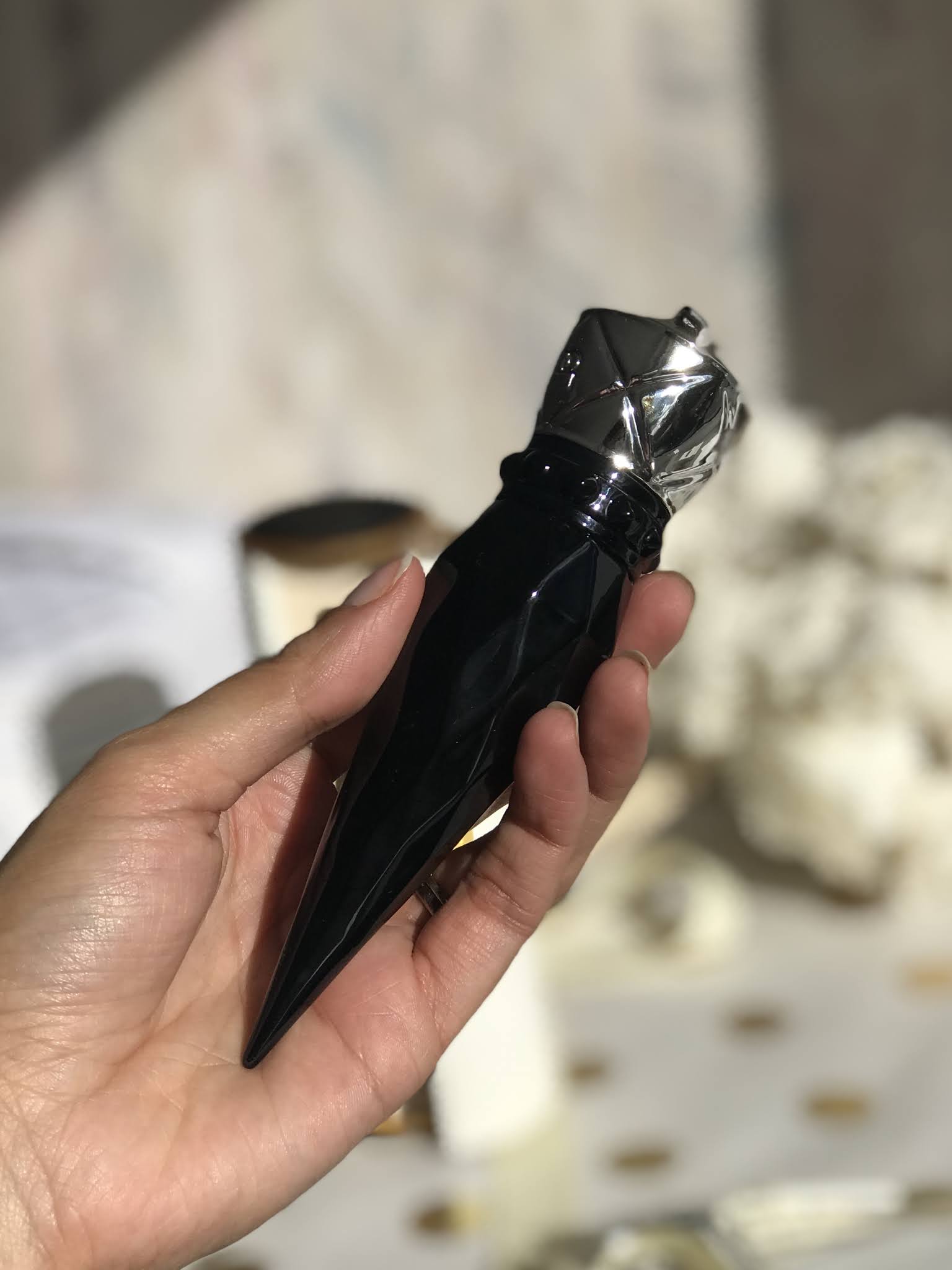 hand holding Iconic black potion paris vial.