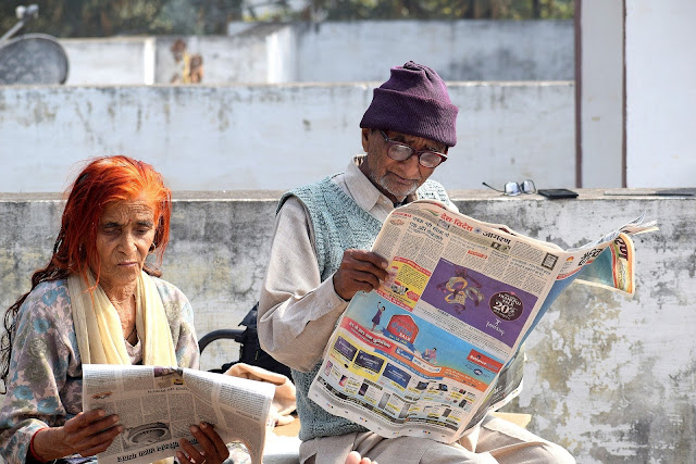 Old couple reading newspaper